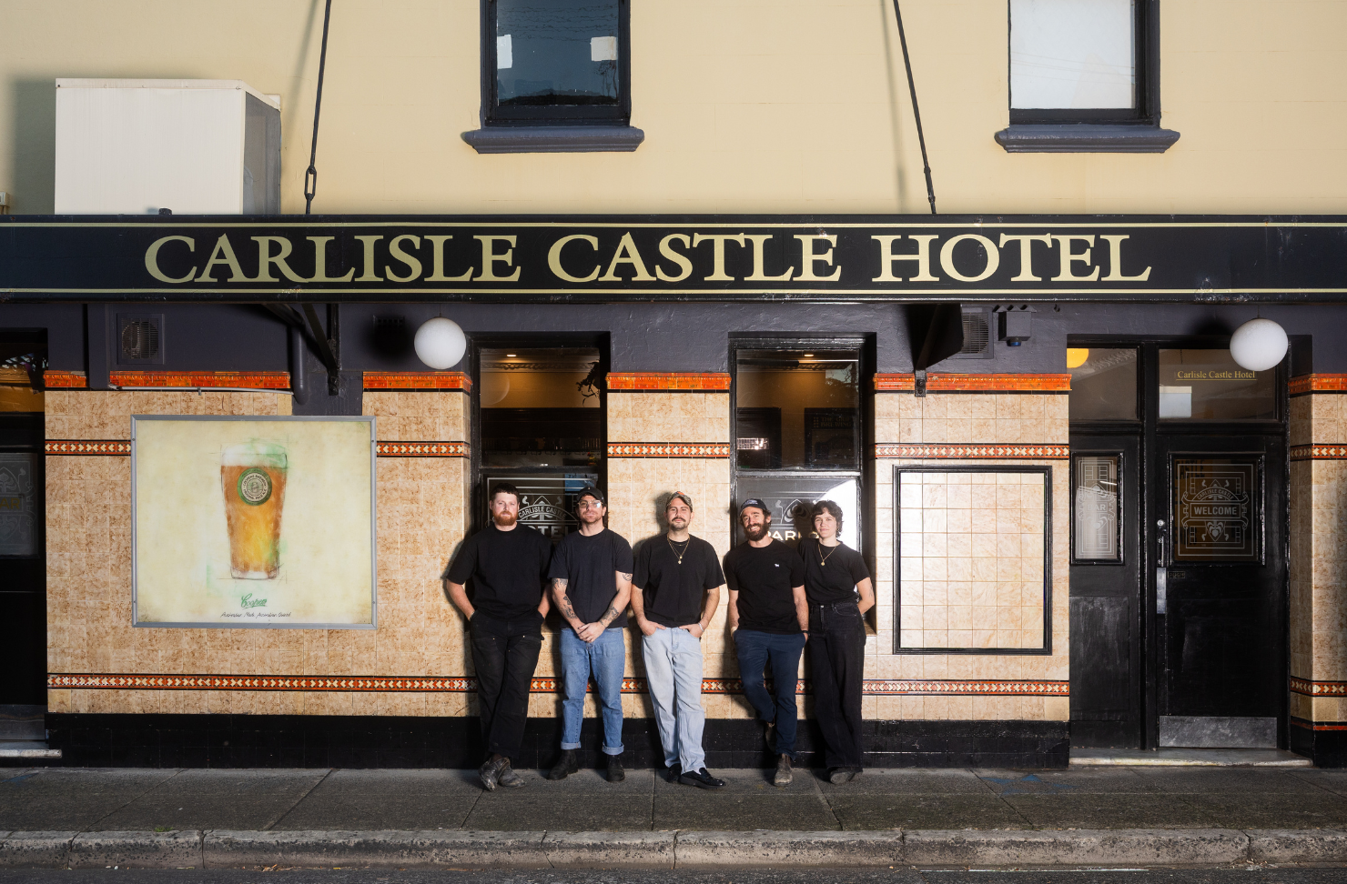 four people posing outside of a pub