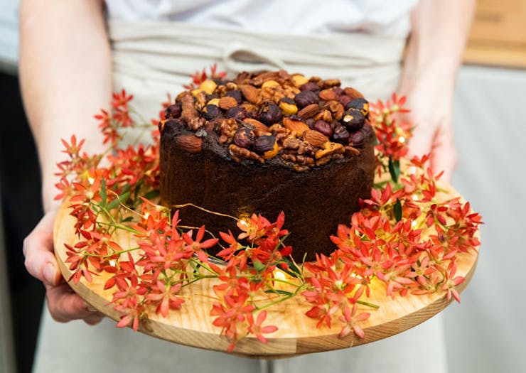 A person holding a Christmas cake decorated with flowers. 