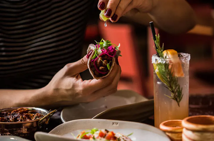 A person squeezing lime into a taco. 