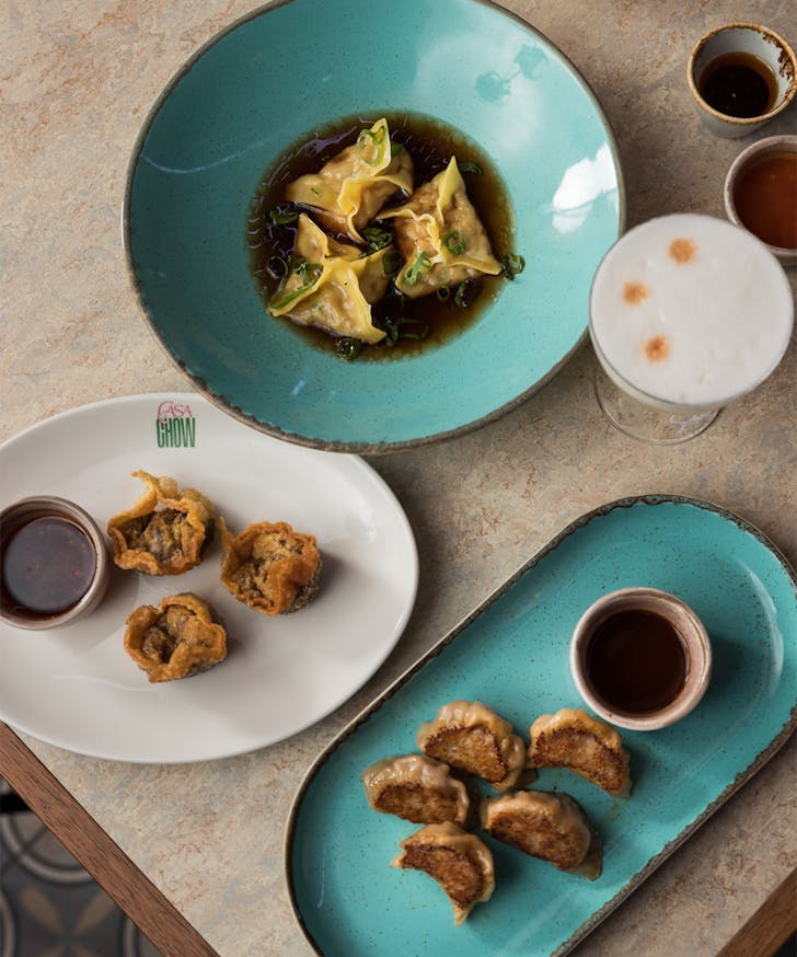 several plates of dim sum with cocktails