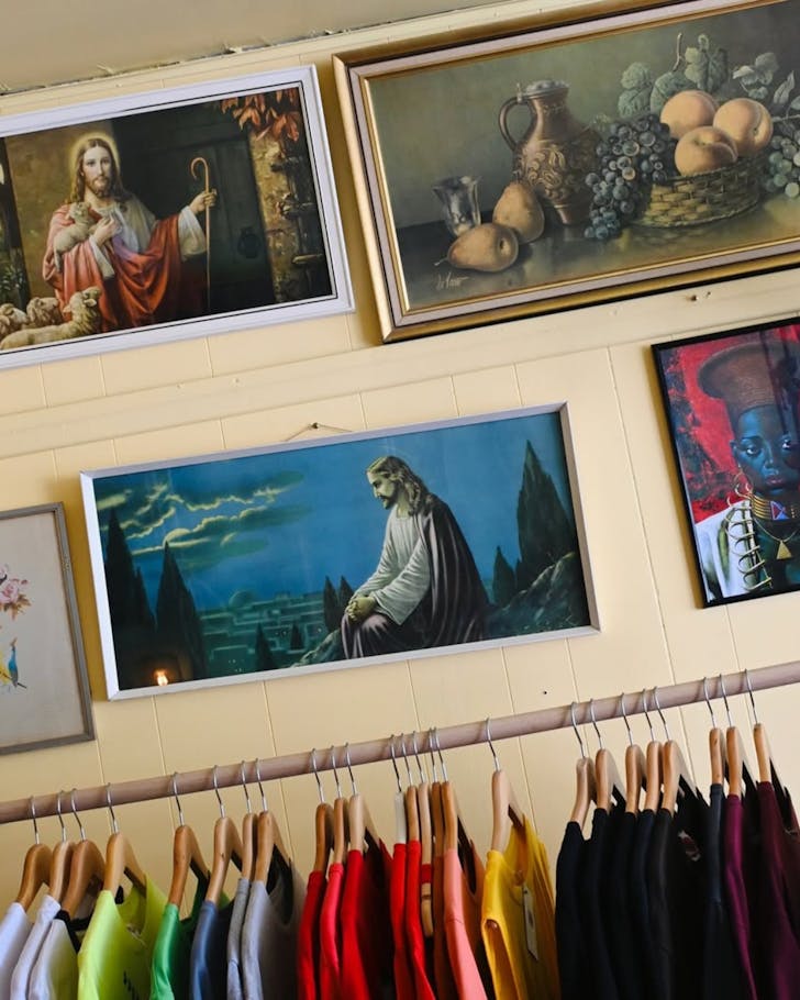 An image of a clothe rack against a wall, and on the wall hangs an artwork of Jesus.