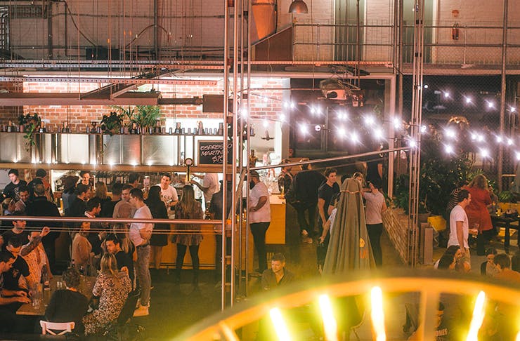 People drinking at a brewery underneath fairy lights.