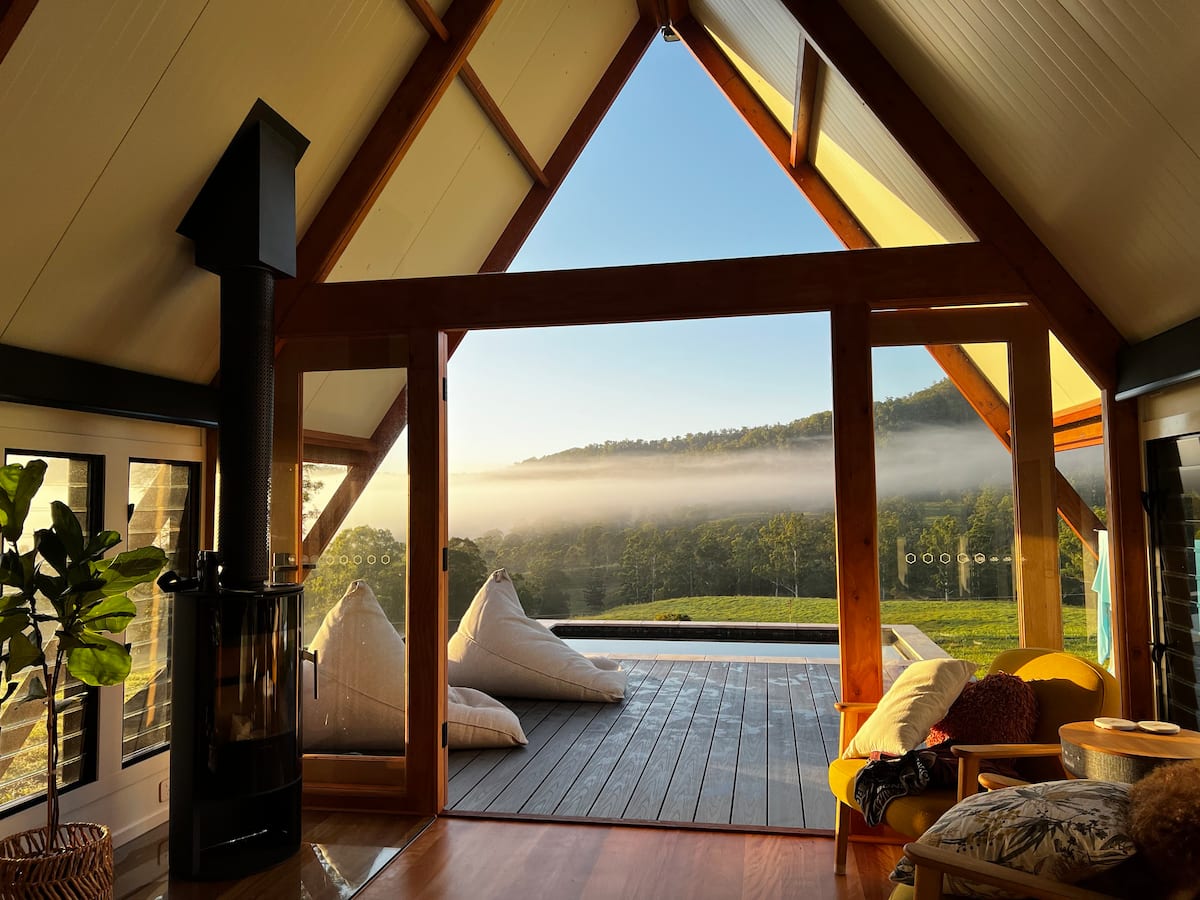 looking out through an a-frame cabin door to a pool surrounded by hills