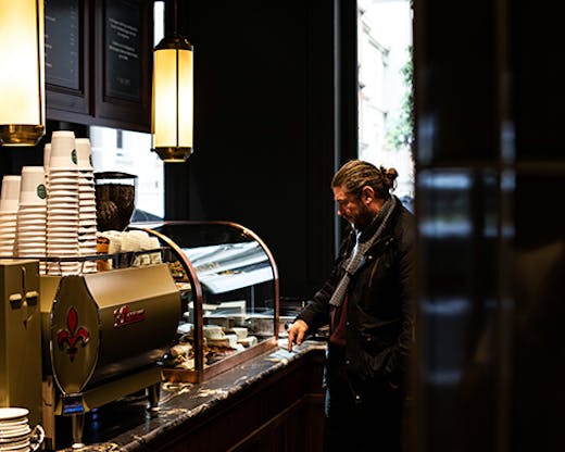 A man standing next to a coffee machine in a moody cafe.