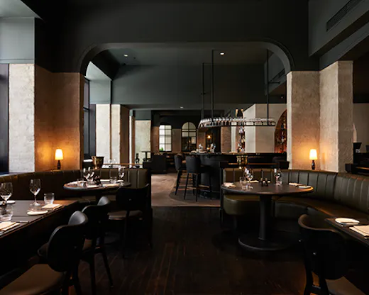 A moody fine diner with wood finishings and warm lighting.