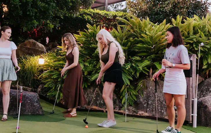 four women playing mini golf