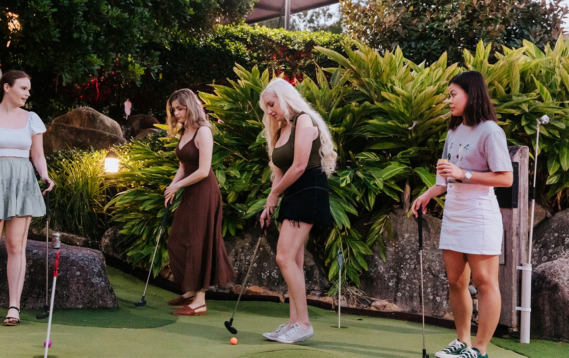 four women playing mini golf