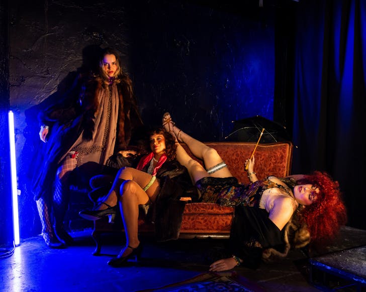 Some of the Chicago The Musical cast lounge over a couch, costumed up.