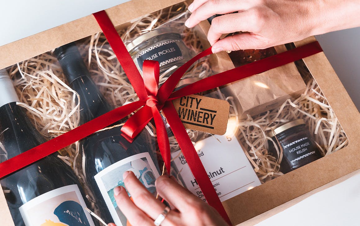 A person tying a ribbon on a Christmas Hamper box