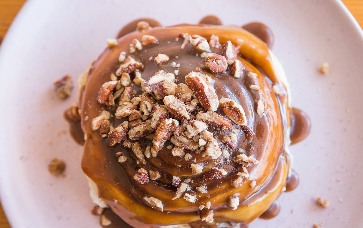 a cinnamon scroll drizzled in caramel sauce