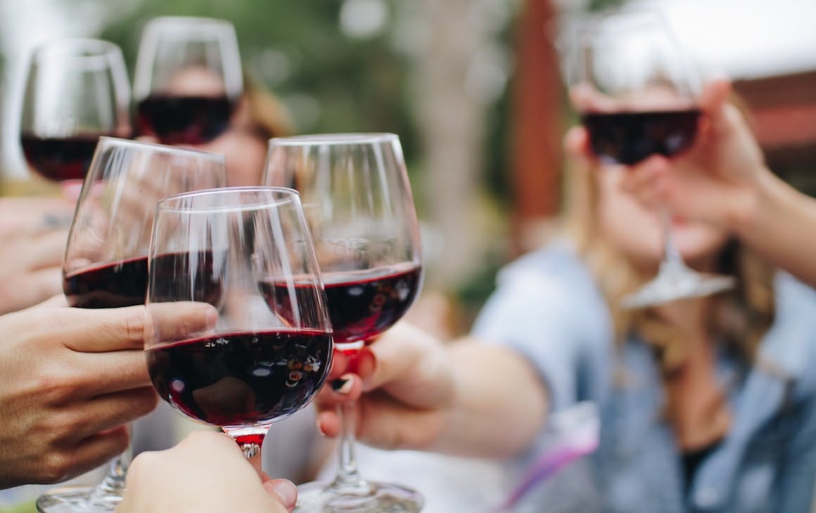 people cheersing with red wine glasses