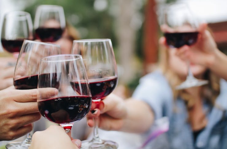 people cheersing with red wine glasses