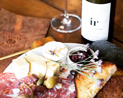 A platter of charcuterie next to a bottle of wine