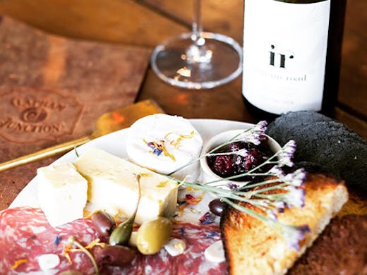 A platter of charcuterie next to a bottle of wine