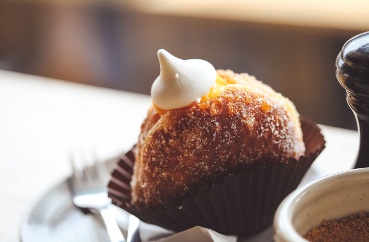 A sugar-dusted donut in Melbourne with a cream on top of it. 