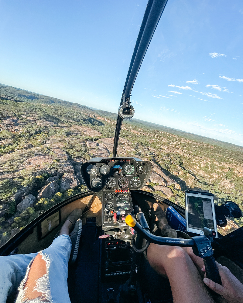 view through the front window of a helicopter, looking at the scenery below