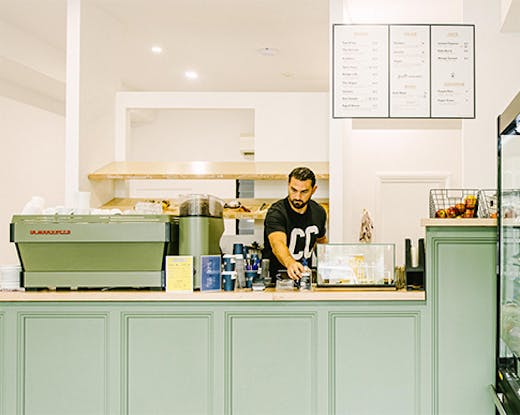 a man behind a mint green counter in a cafe