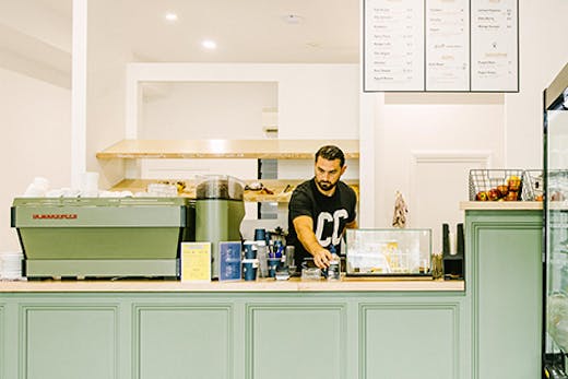 a man behind a mint green counter in a cafe