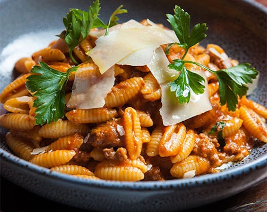 a bowl of shell pasta with bolognaise sauce