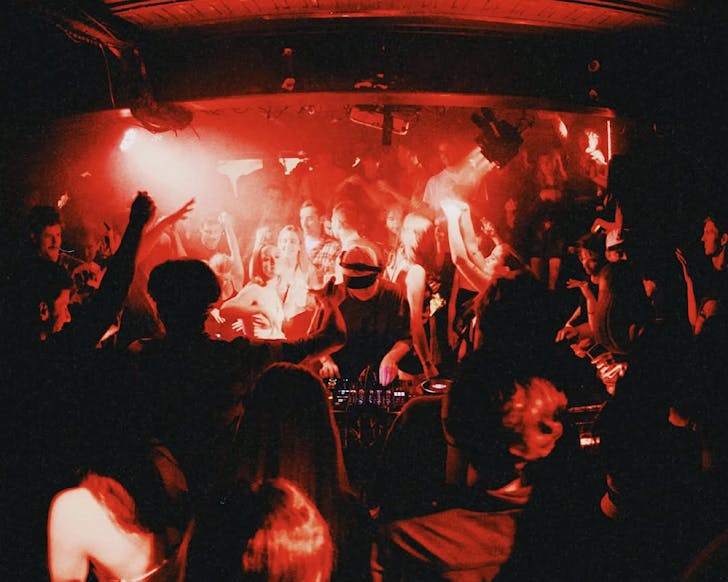 The Collekt crew DJ down in a red-lit venue; the crowd surrounds them.