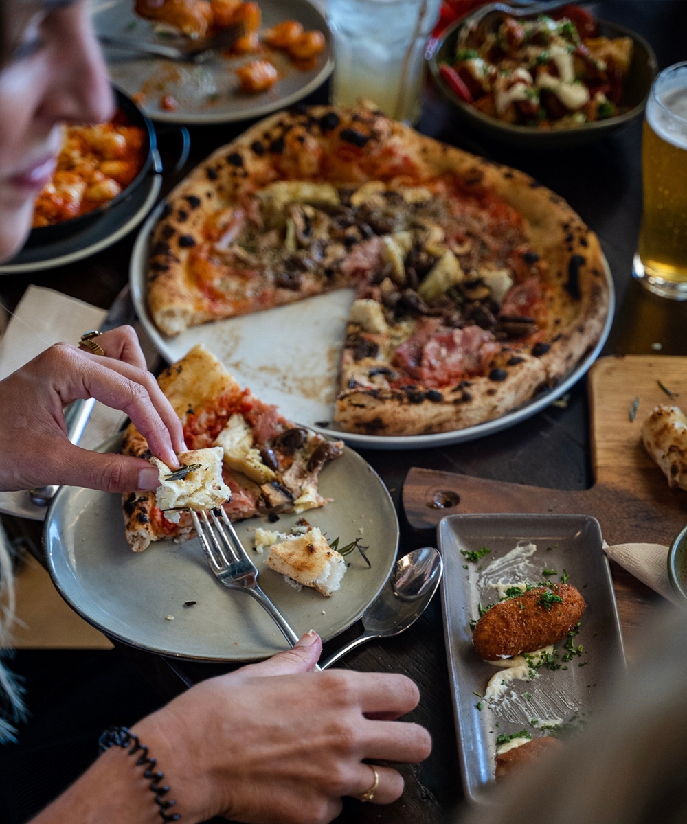 a table loaded with pizza and tapas