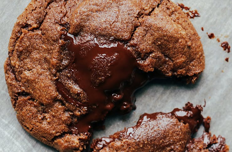 A torn chocolate chip cookie with a molten chocolate interior.