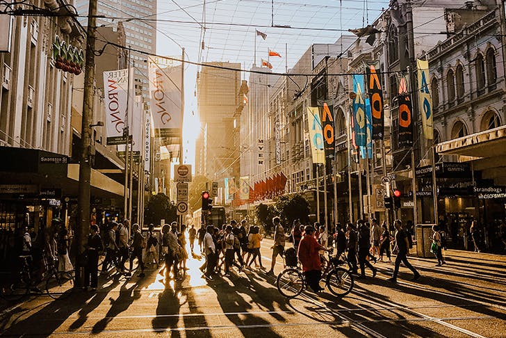 a crowd of people walking in melbourne at golden hour