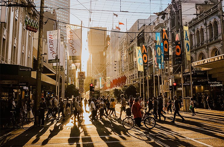 a crowd of people walking in melbourne at golden hour