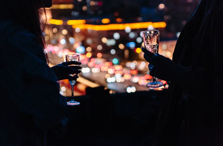 A couple holding champagne flutes in a darkened bar.