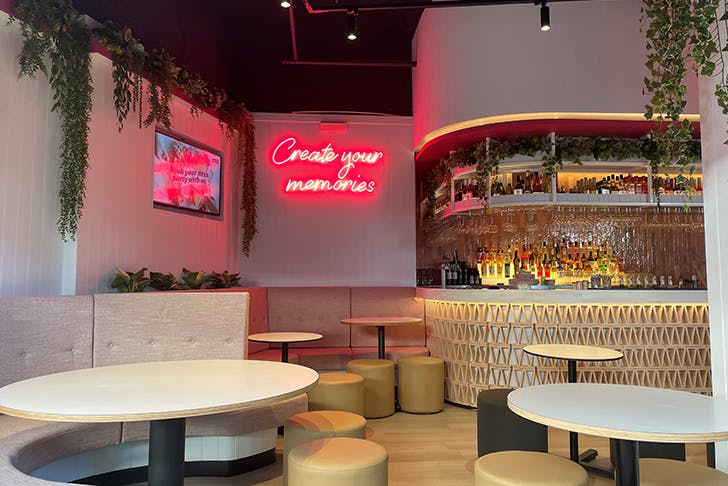 the interior of a dessert bar with a neon sign