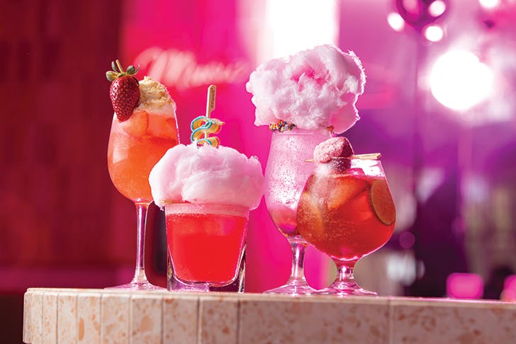 four pink cotton candy-topped cocktails 