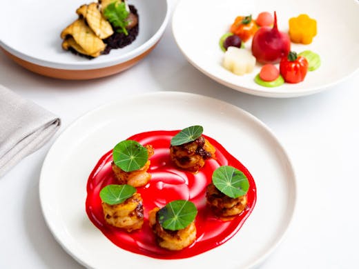 Three plates featuring brightly coloured, artistic dishes from COYA cromer. 