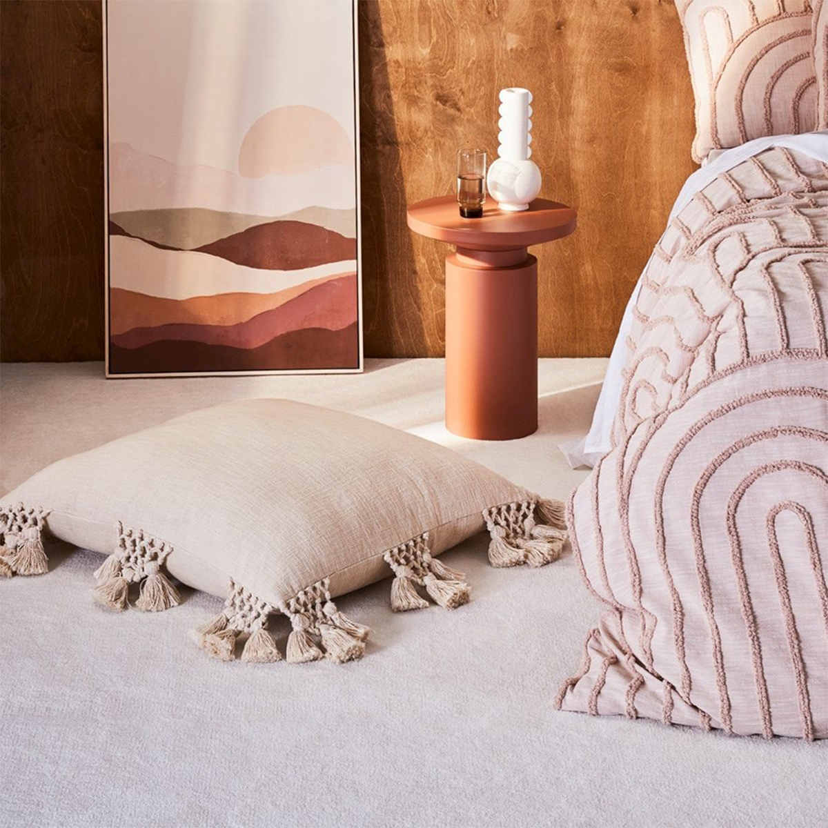 a bed, bedside table and a painting all in shades of dusty pink