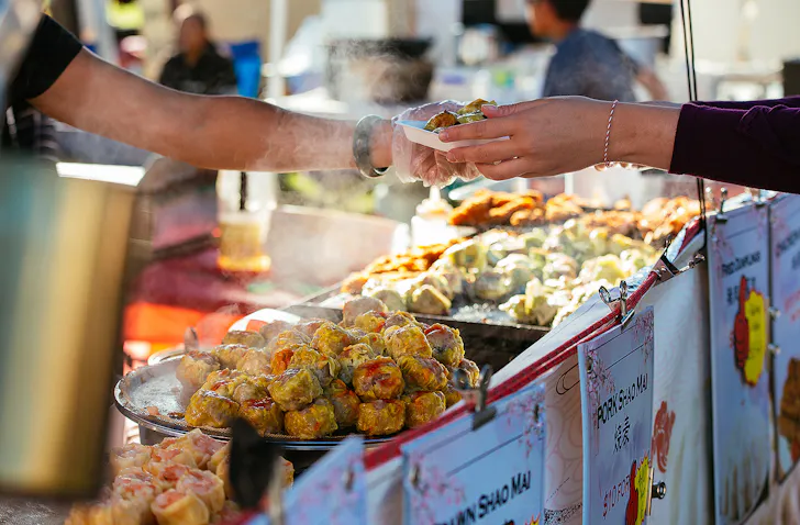Hands exchange delicious looking snacks at the cultural fest.