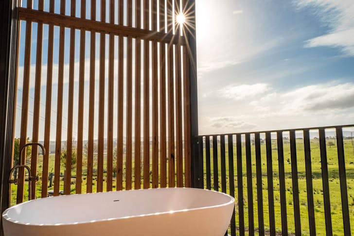 An outdoor bath tub with a view across green paddocks