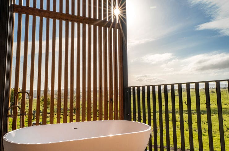 An outdoor bath tub with a view across green paddocks