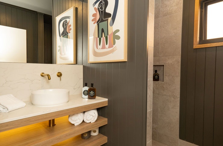 A colourful abstract painting in a bathroom with dark grey tiles