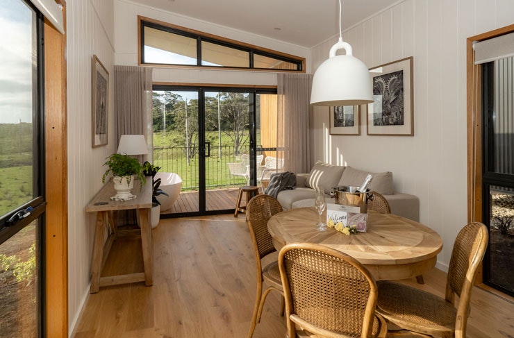 A living room and dining room with a round wooden dining table and plush grey couch