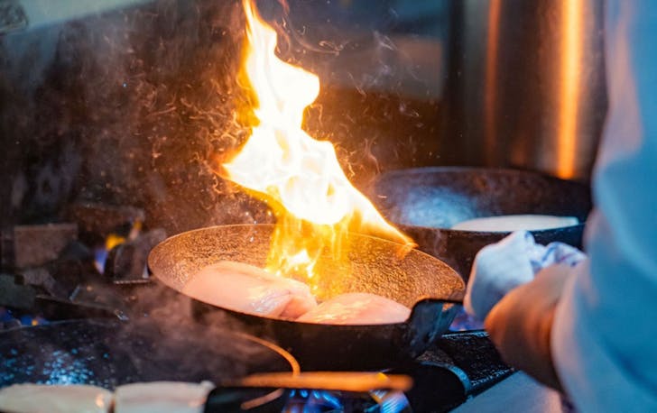 Chef cooking in a pan with flames