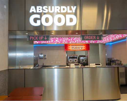 Chrome front counter at CUSS in Newtown, with the logo Absurdly Good in neon signage above.