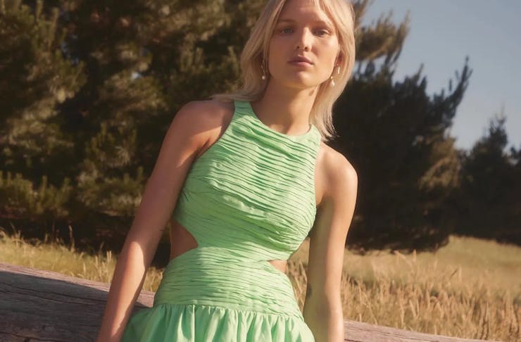 A model wearing a green cut out dress from Aje