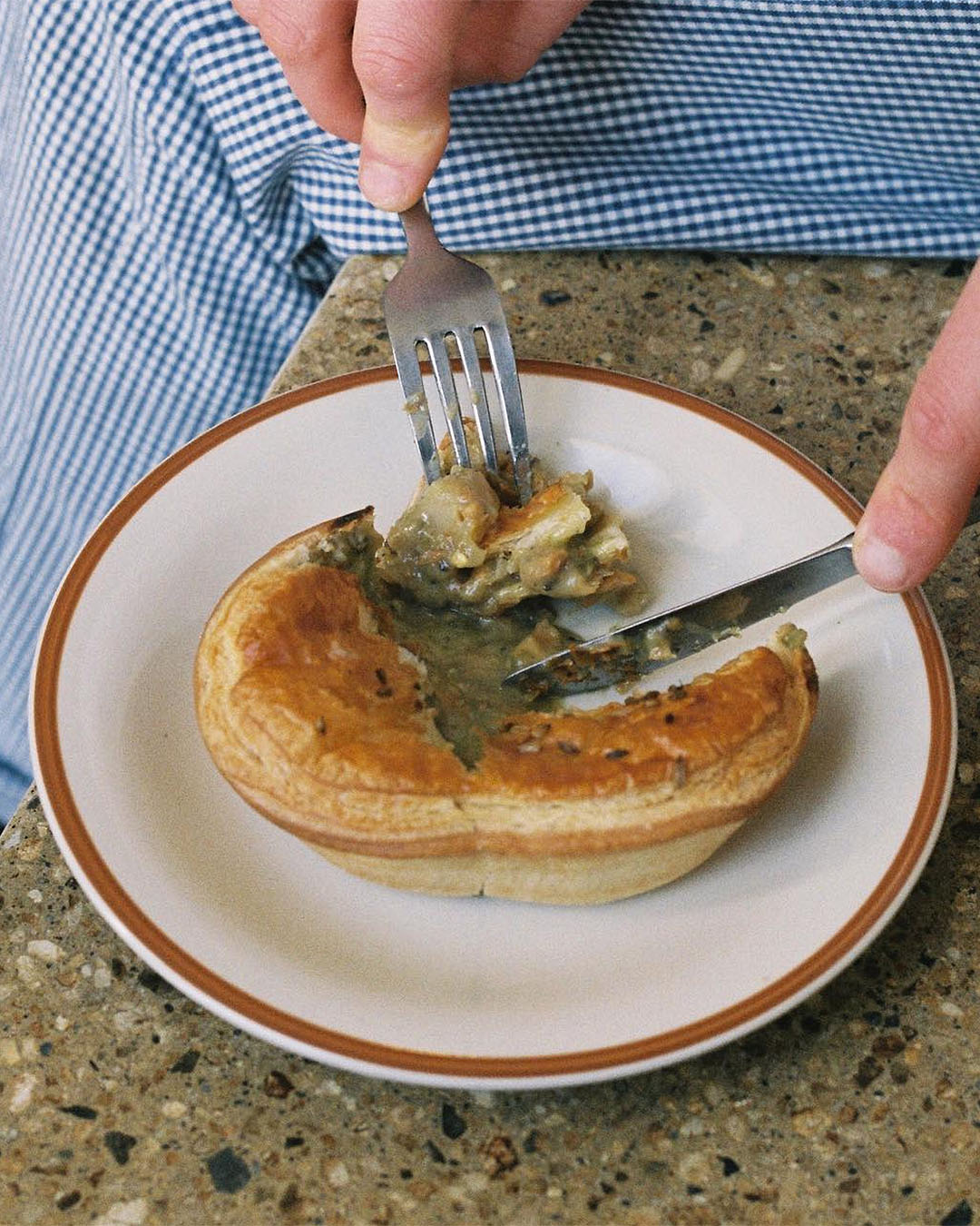 A person tucks into a mouthwatering bolognese and provolone pie with a knife and fork. 