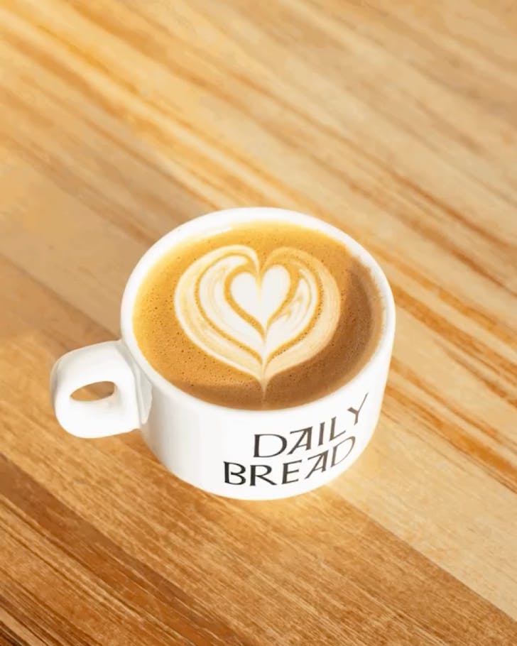 A freshly brewed coffee of Daily Roast in a special white Daily Bread-branded cup.