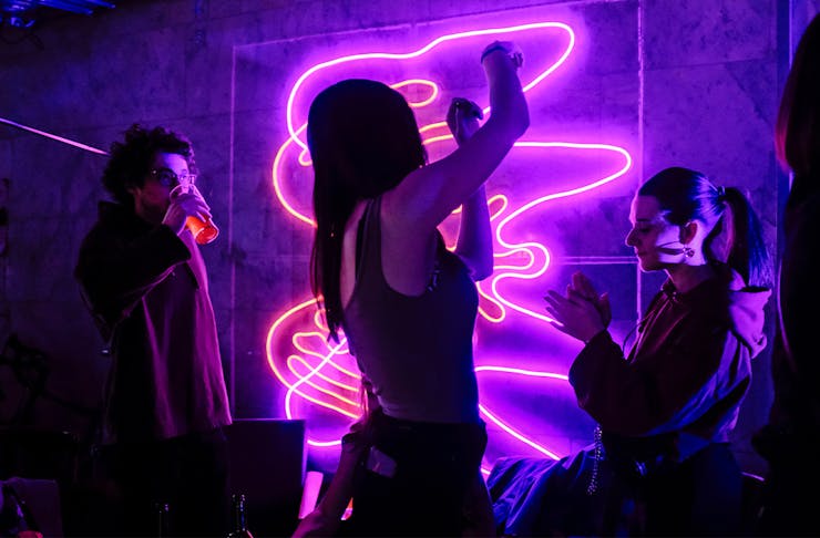 a woman dancing in front of a neon sign