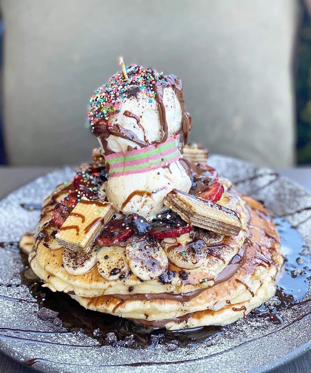 A stack of pancakes topped with ice cream and more