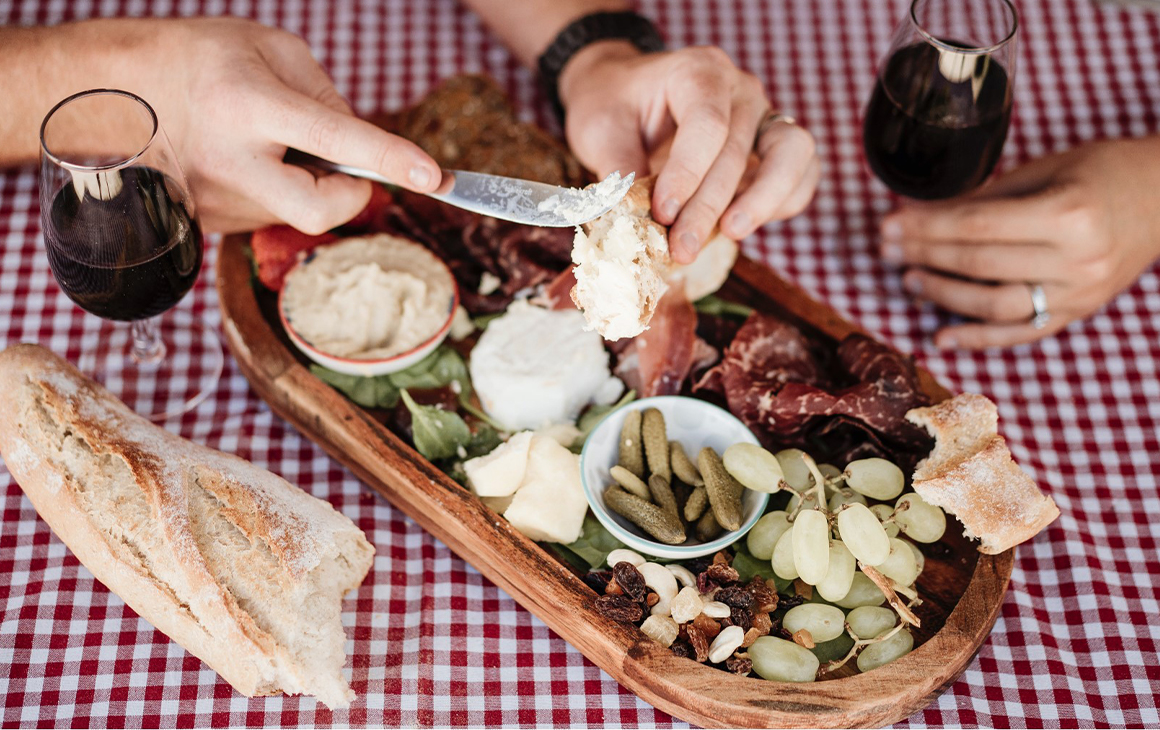 a charcuterie platter on a picnic blanket with wine
