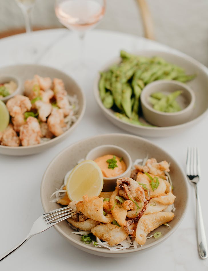 several plates of bar bites, with a bowl of crisp calamari at the forefront
