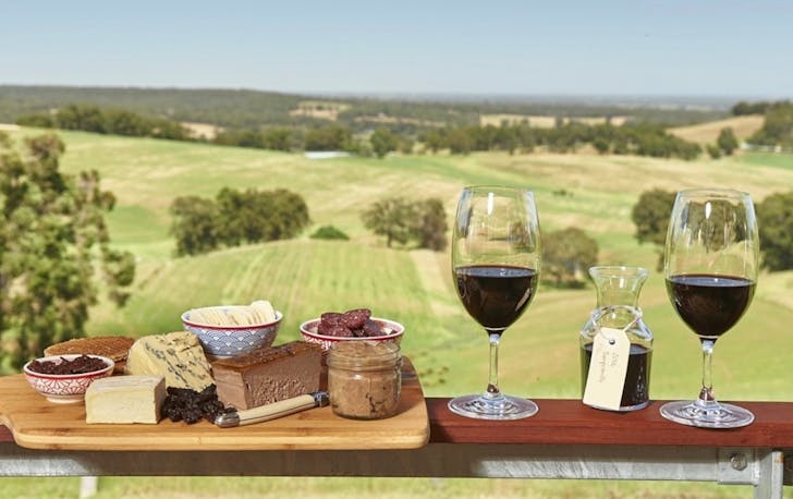 Things to do Ferguson Valley - two glasses of wine and a cheese board rest on balcony overlooking rolling green hills