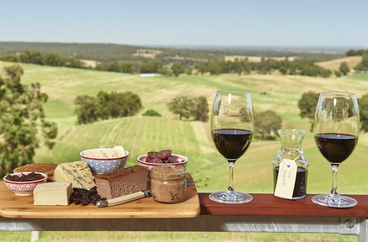 Things to do Ferguson Valley - two glasses of wine and a cheese board rest on balcony overlooking rolling green hills