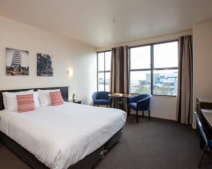 A large white bed, perfect for bouncing on, at Distinction New Plymouth, one of the best hotels in New Plymouth. 